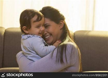 Mother hugging and caressing her baby in living room