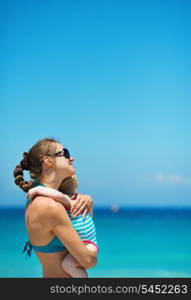 Mother hugging baby on beach