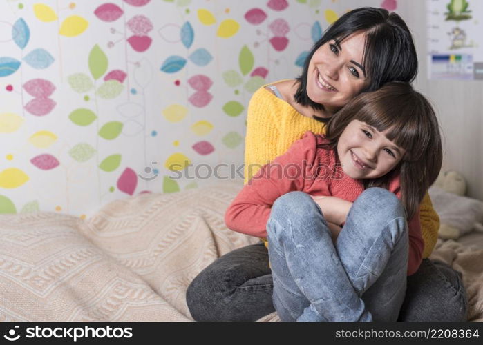 mother hugging daughter from bed