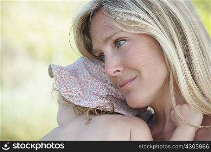 Mother hugging toddler wearing sunhat