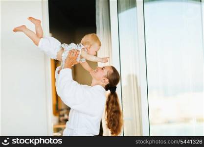 Mother in bathrobe playing with baby on terrace
