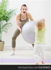 Mother in sportswear playing with baby at gym