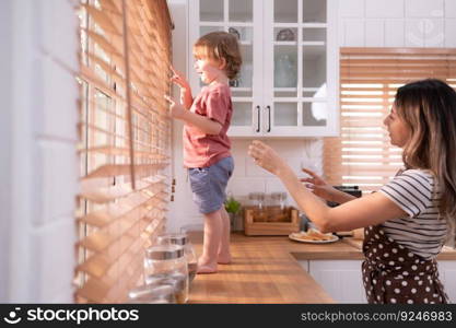 Mother in the kitchen of the house with a small child. Play and have fun cooking dinner together.