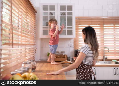 Mother in the kitchen of the house with a small child. Play and have fun cooking dinner together.