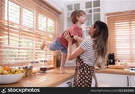 Mother in the kitchen of the house with a small child. Play and have fun cooking dinner together.