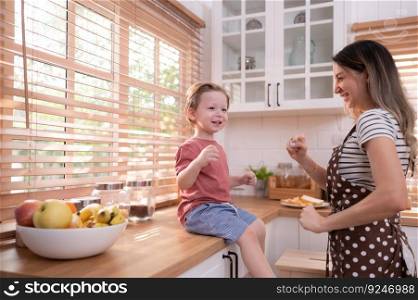 Mother in the kitchen of the house with a small child. Play and have fun cooking dinner together.