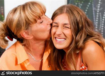 Mother is kissing her daughter as a sign of love