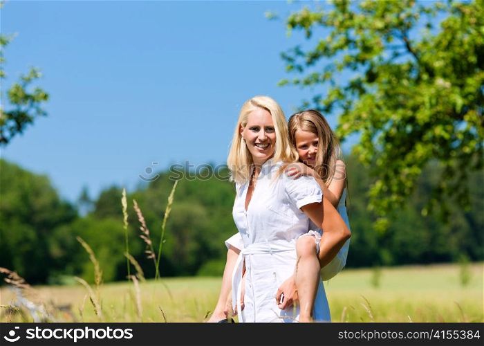 Mother is playing with daughter in meadow on a summer day