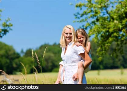 Mother is playing with daughter in meadow on a summer day