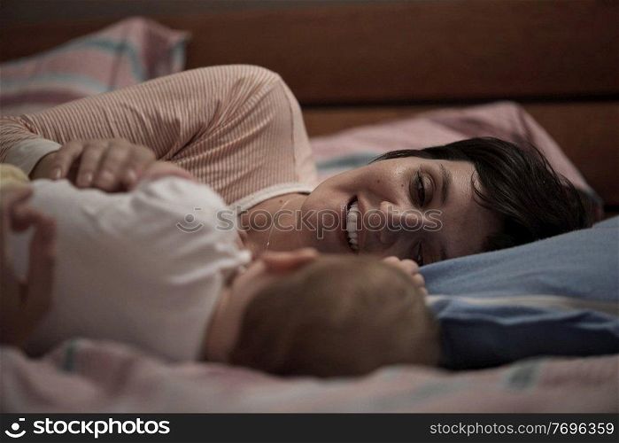 mother is playing with newborn baby at home