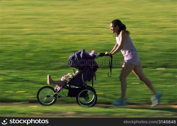 Mother Jogging In The Park With Her Baby In A Stroller
