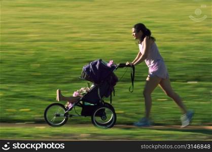 Mother Jogging In The Park With Her Baby In A Stroller