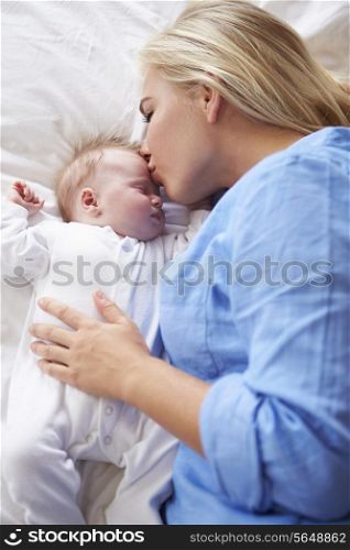 Mother Kissing Baby Girl As They Lie In Bed Together
