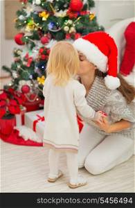 Mother kissing baby near Christmas tree