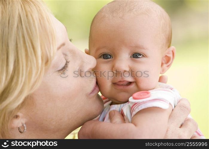 Mother kissing baby outdoors