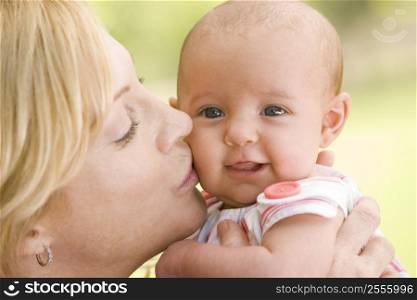Mother kissing baby outdoors