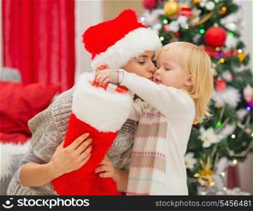Mother kissing baby taking out present from Christmas sock