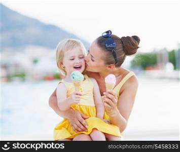 Mother kissing baby while eating ice cream