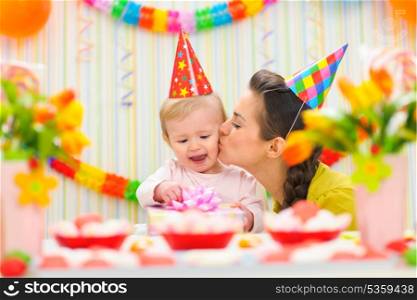 Mother kissing her happy while baby checking present