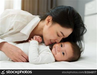 mother kissing her infant baby on a bed