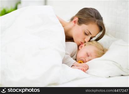 Mother kissing sleeping baby