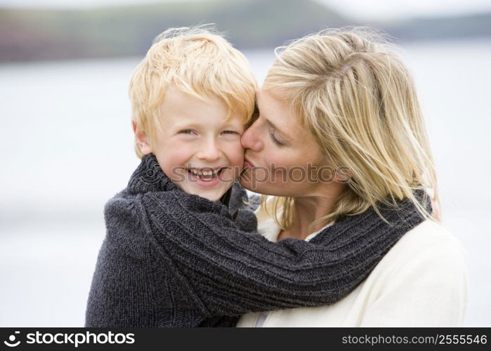 Mother kissing son at beach smiling