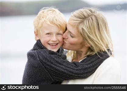 Mother kissing son at beach smiling
