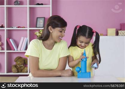 Mother looking at daughter playing with blocks at home