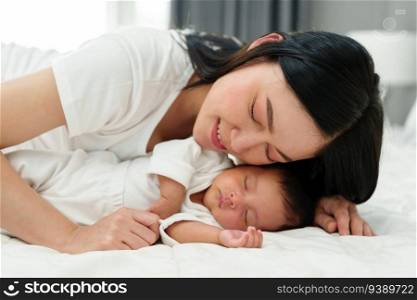 mother lying down and loving her newborn baby on a bed. 