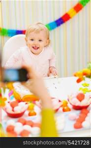 Mother making photos of baby on birthday party