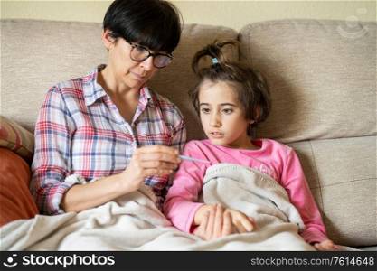 Mother measuring her daughter&rsquo;s temperature with a digital thermometer to check for fever. Mother measuring her daughter&rsquo;s temperature to check for fever