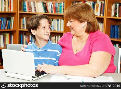 Mother or teacher, helping a little boy study in the library.