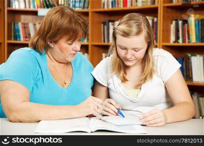 Mother, or teacher, helping a teenage girl with her homework.