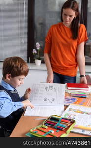 mother or teacher helping kid with schoolwork