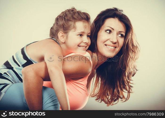 Mother parent giving kid piggyback ride.. Young mother mom parent woman giving kid little girl piggyback ride. Childhood fun. Happy family.