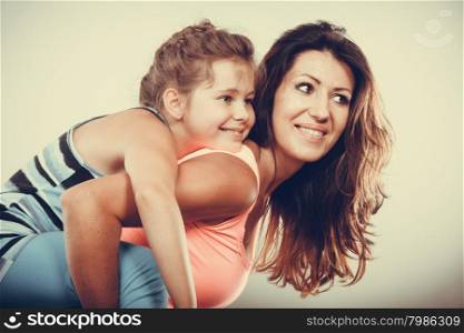 Mother parent giving kid piggyback ride.. Young mother mom parent woman giving kid little girl piggyback ride. Childhood fun. Happy family.