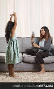 Mother photographing daughter in dance pose