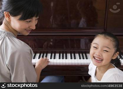 Mother playing the piano for her daughter