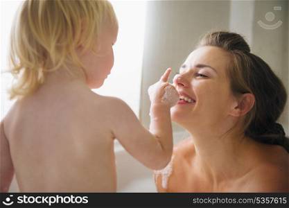 Mother playing with baby in bathtub
