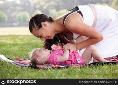 mother playing with daughter in the park in summer