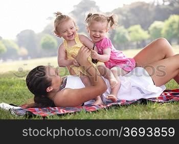 mother playing with daughters in the park in summer
