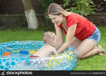Mother playing with her baby boy in inflatable swimming pool