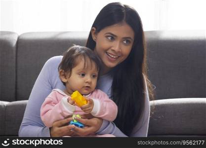 Mother playing with her baby in living room with toy blocks