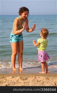 Mother plays with daughter on beach, okee-dokee