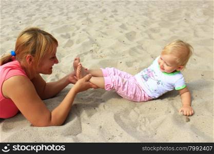 mother plays with her baby plays on the sand. mother plays with her baby plays on the river sand