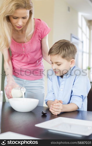 Mother pouring milk for son at table