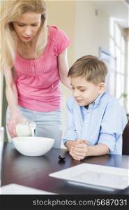 Mother pouring milk for son at table
