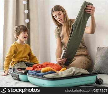 mother preparing traveling luggage with son