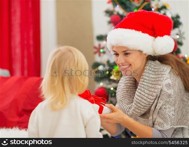 Mother presenting baby girl Christmas present