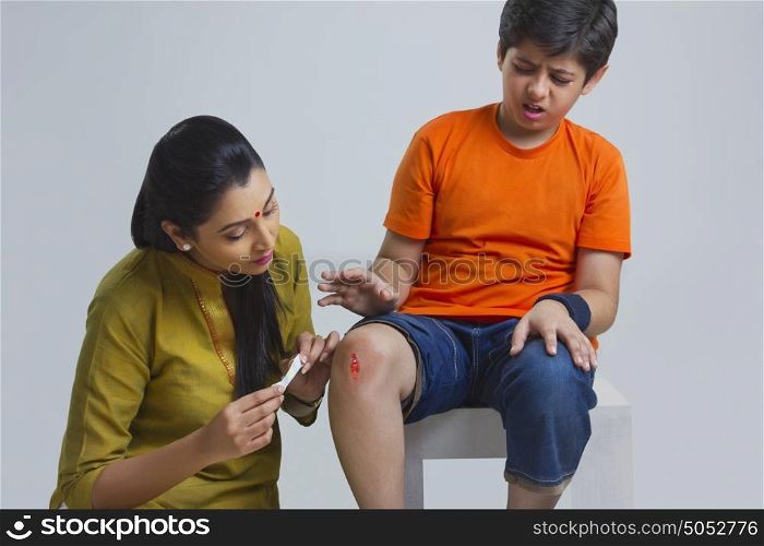 Mother putting bandage on sons wound